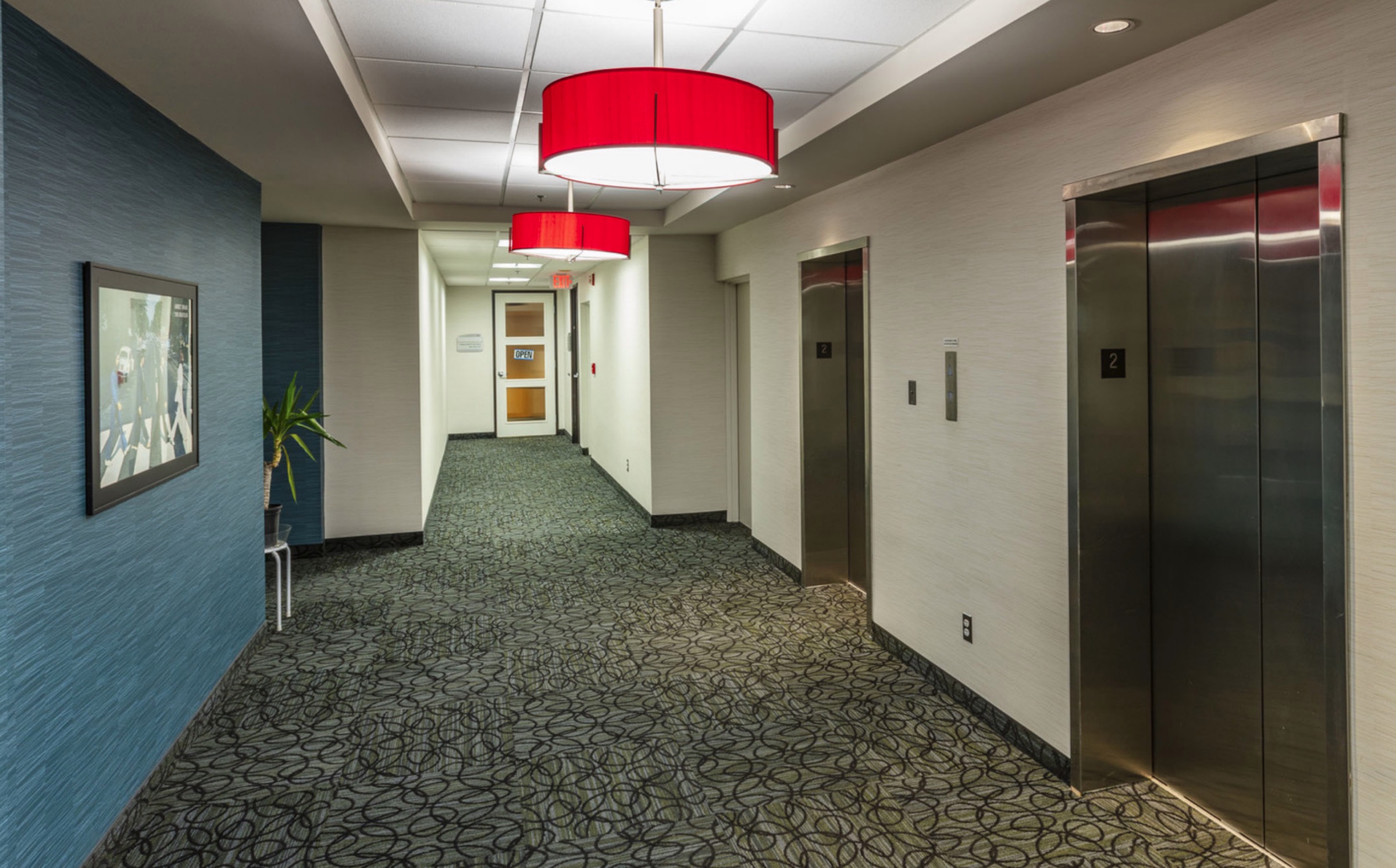 Common-area corridor with pendant lighting and elevators